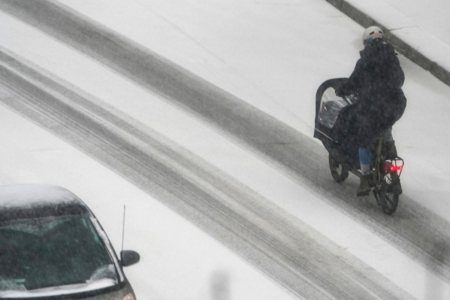 Eine Frau fährt mit einem Lastenfahrrad in Hamburg über eine verschneite Straße.