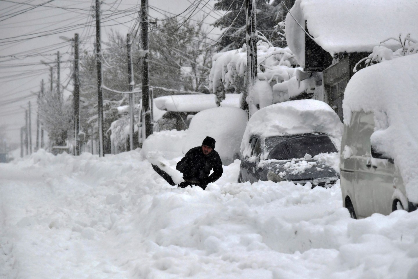 Ein Mann in Isperich schaufelt Schnee, um sein Auto zu befreien.