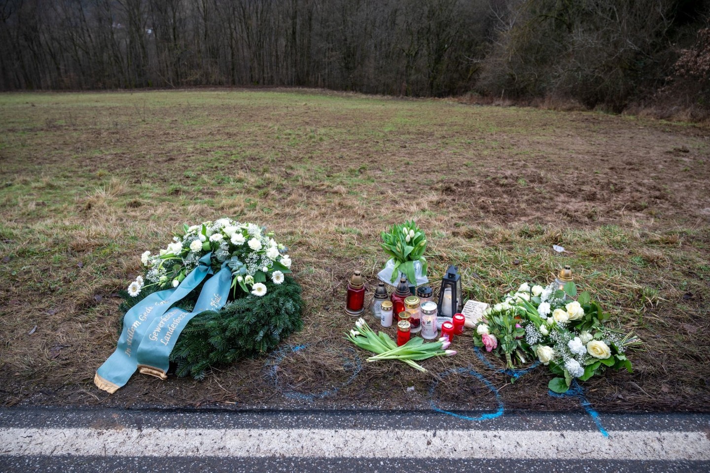 Ein Kranz sowie Blumen und Kerzen liegen am Tatort an der Kreisstraße 22 bei Ulmet (Rheinland-Pfalz) zum Gedenken. Dort wurden zwei Polizisten bei einer Verkehrskontrolle getötet.