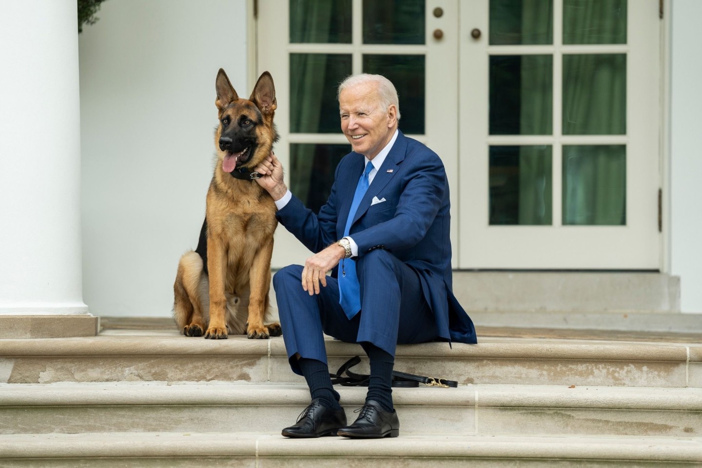 US-Präsident Joe Biden sitzt mit seinem Hund auf den Stufen vor dem Weißen Haus.