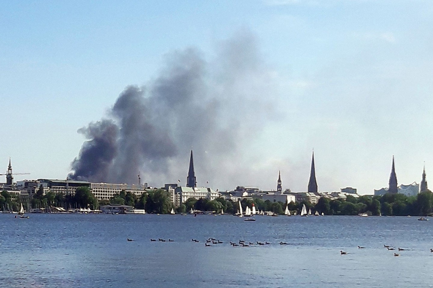 Eine Rauchwolke ist über der Alster in Hamburg zu sehen. Auf einem zehnstöckigen Haus in der Hamburger HafenCity ist es am Freitagnachmittag zu mehreren Explosionen gekommen.