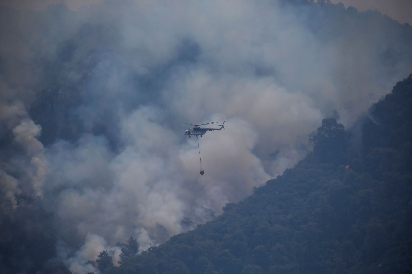 Ein Hubschrauber transportiert Löschwasser, um einen Waldbrand in der Türkei zu löschen.