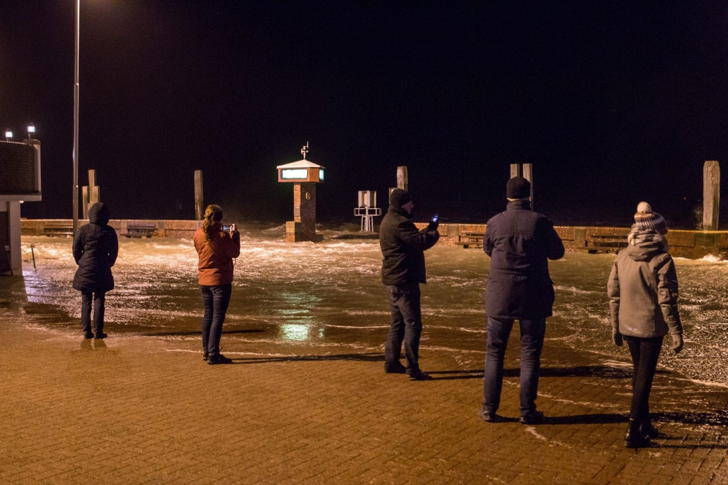 Eine Sturmflut überspült die Mole im Hafen von Norddeich in Ostfriesland.