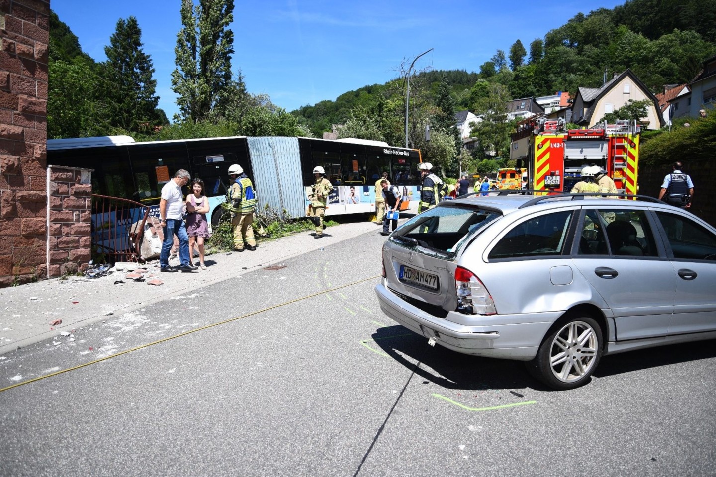 Einsatzkräfte begutachten die Unfallstelle, an der der Linienbus gegen das Wohnhaus krachte.