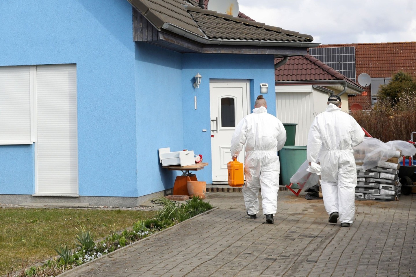 Mitarbeiter der Kriminaltechnik gehen in das Haus in Rövershagen, in dem drei Menschen getötet worden sein sollen.