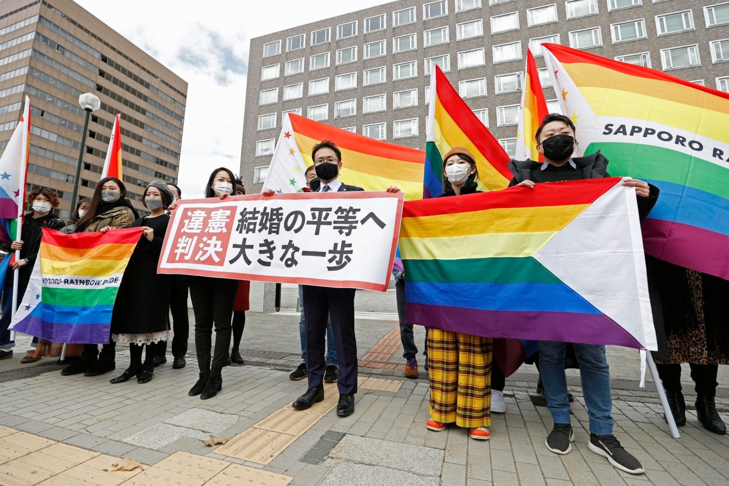 Anwälte der Kläger und Unterstützer halten 2021 Regenbogenflaggen und ein Transparent mit der Aufschrift: «Verfassungswidriges Urteil» vor dem Bezirksgericht Sapporo hoch.