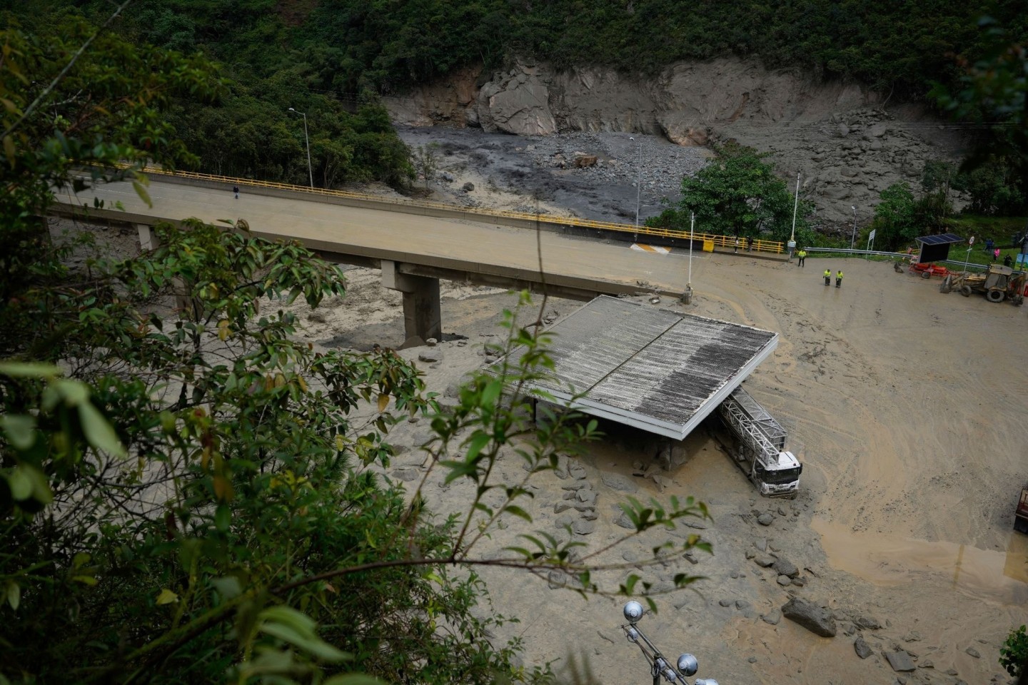 Ein schlammbedeckter Lastwagen steht nach einem Erdrutsch unter einer Brücke.