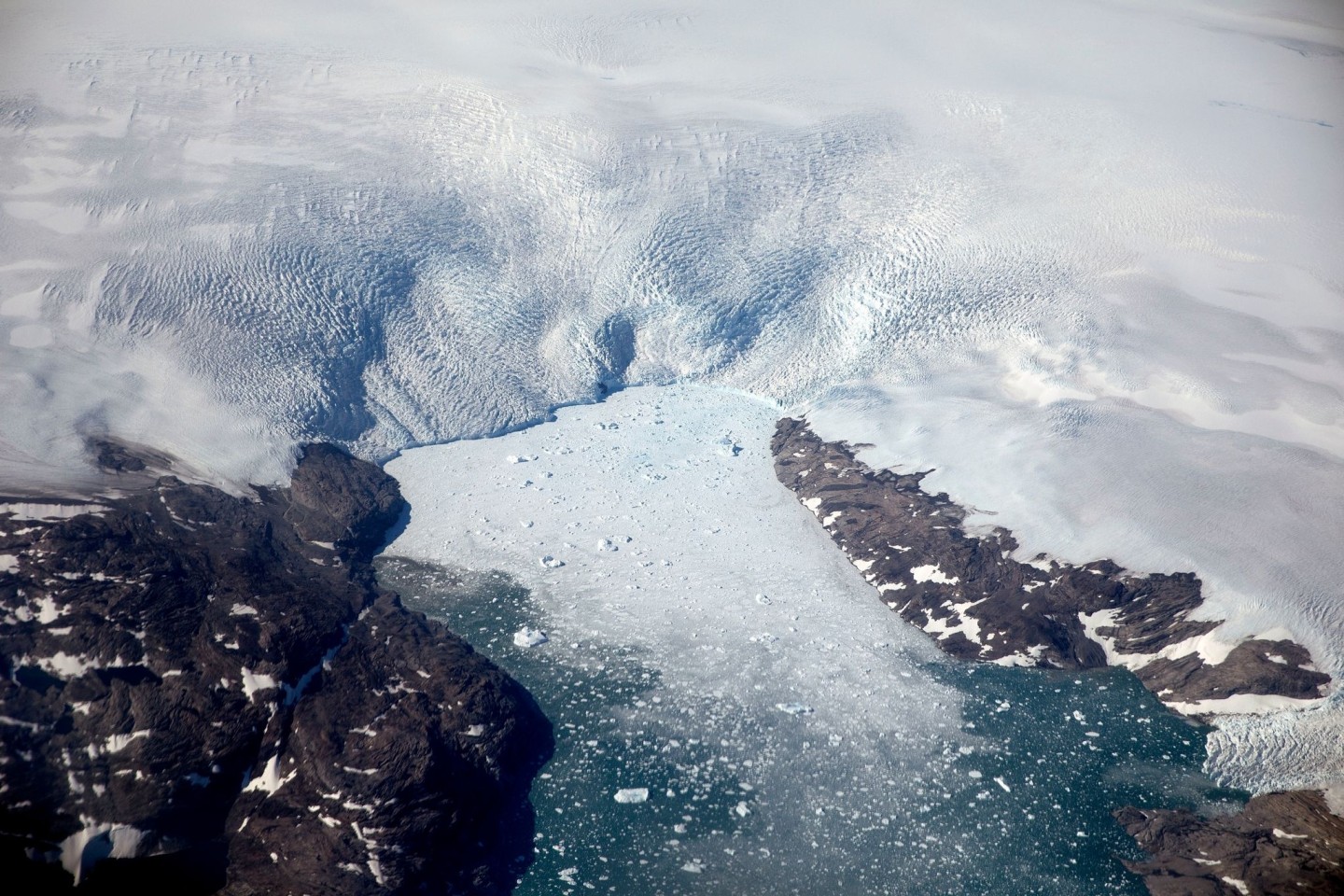 Eisberge brechen von einem Gletscher in einen Fjord in Grönland. Schmelzen die Gletscher und Eisflächen etwa in Grönland, steigen die Meeresspiegel.
