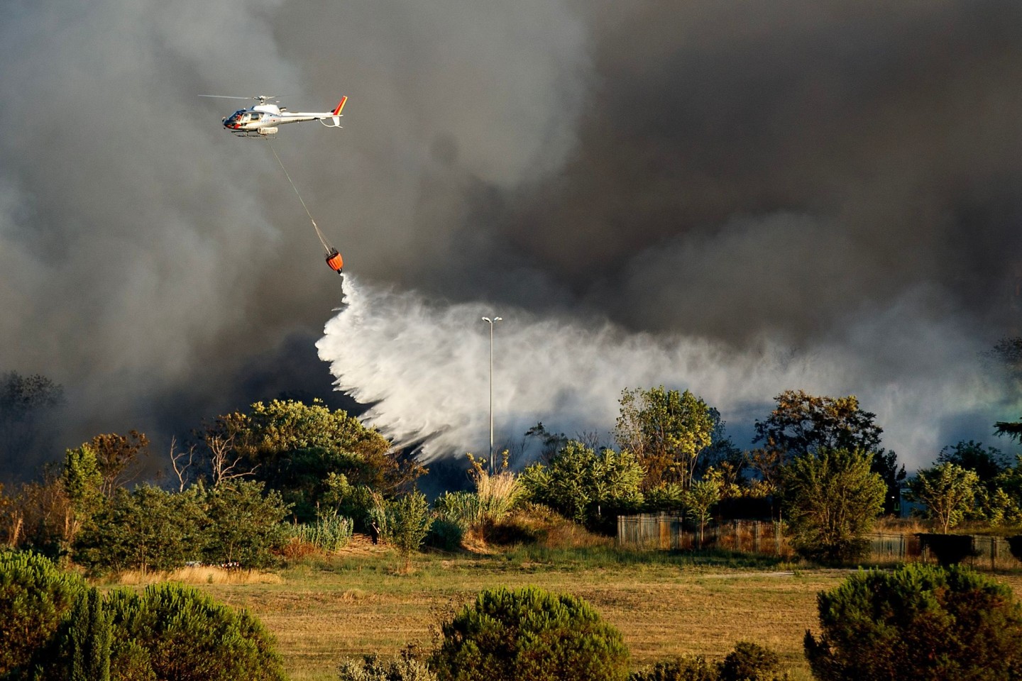 Ein Hubschrauber wirft Wasser ab, um ein Feuer im Centocelle-Park unweit von Rom zu löschen.