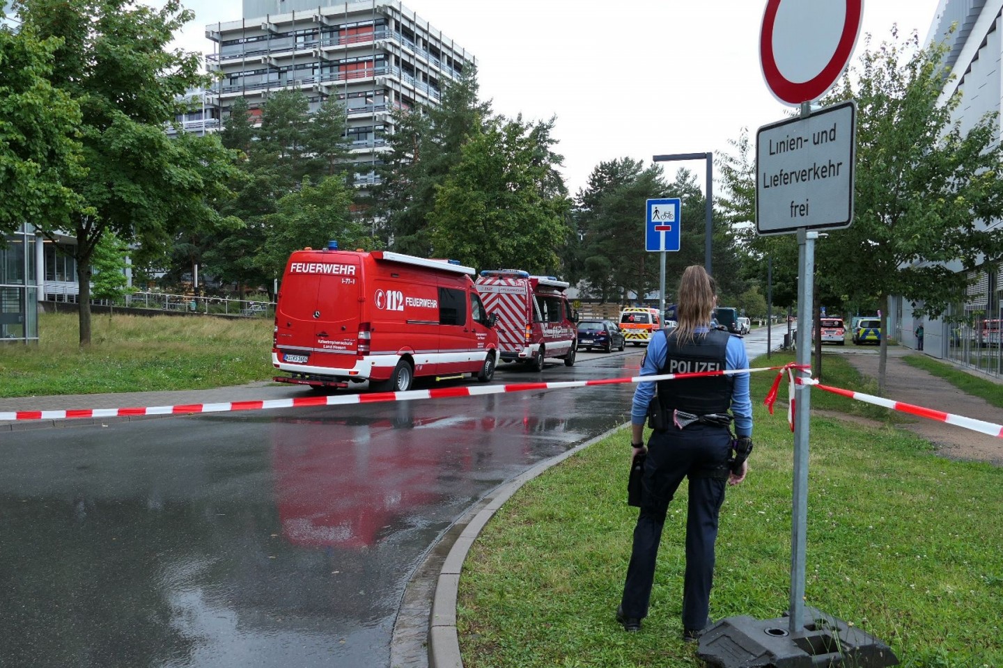 Eine Beamtin und Einsatzfahrzeuge der Feuerwehr auf dem Campus der TU Darmstadt.