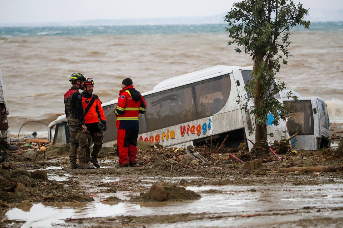 Rettungskräfte auf Ischia neben einem Bus, der durch schwere Regenfälle weggeschwemmt wurde.