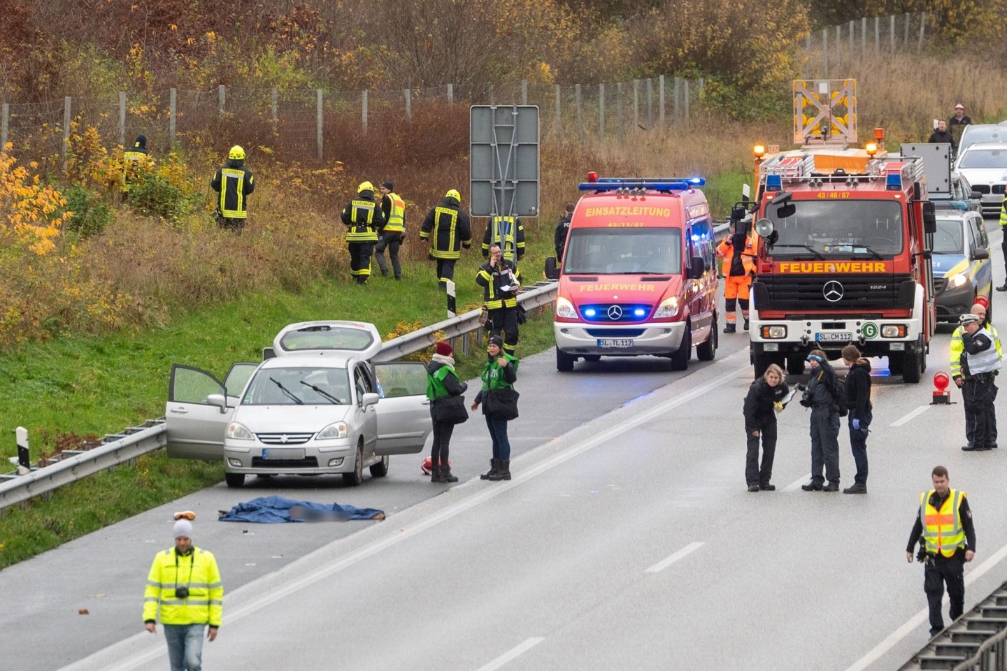 Polizisten und Rettungskräfte stehen neben dem Leichnam der jungen Frau auf der Autobahn 7.