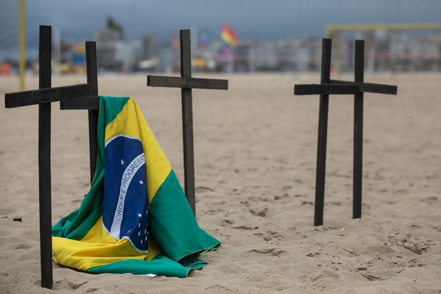 Eine brasilianische Flagge hängt an der Copacabana an einem der Kreuze bei einer Gedenkveranstaltung für einen ungewöhnlichen Corona-Protest.