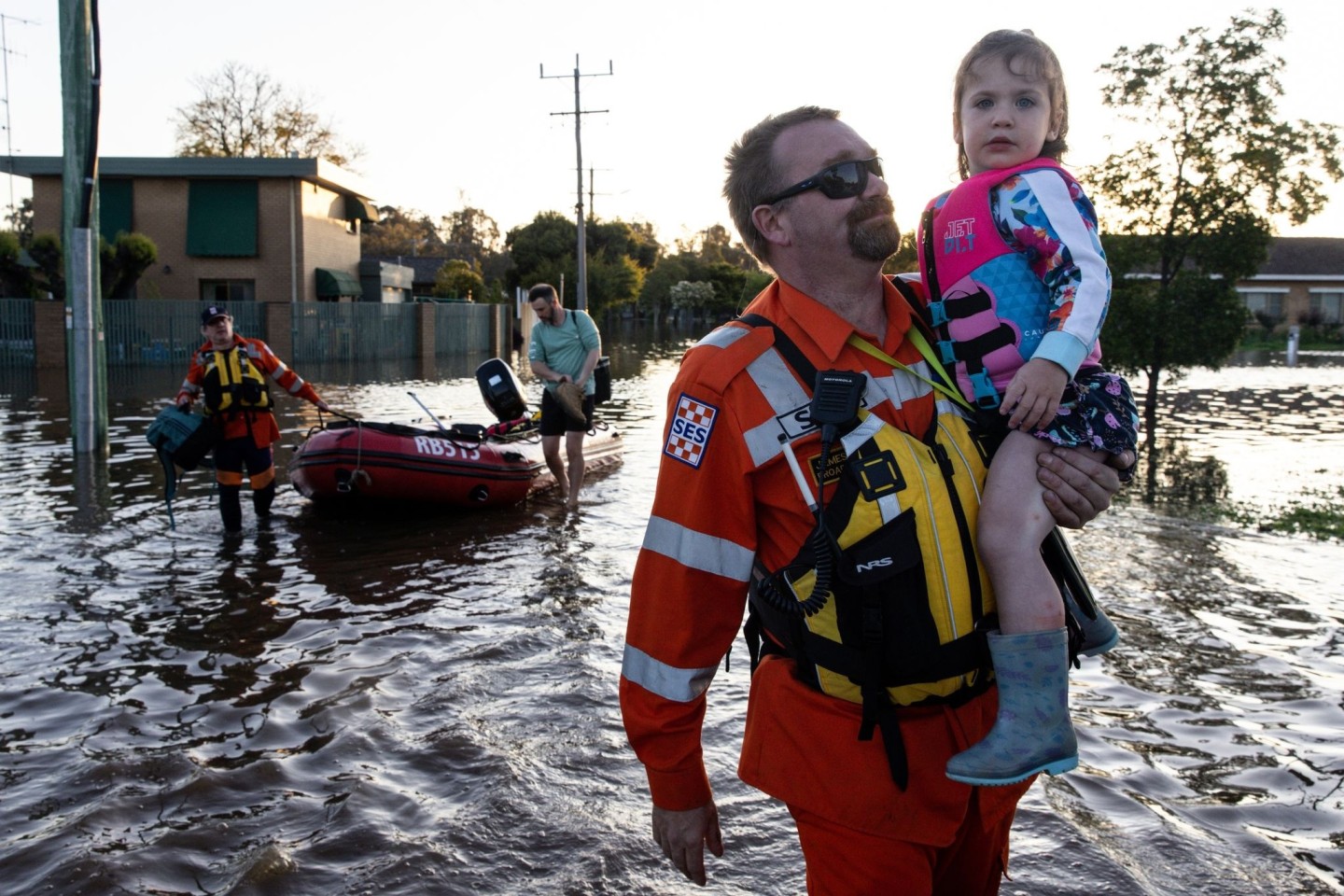 Mitarbeiter des australischen Katastrophenschutzes helfen einer Familie beim Verlassen ihres Hauses.