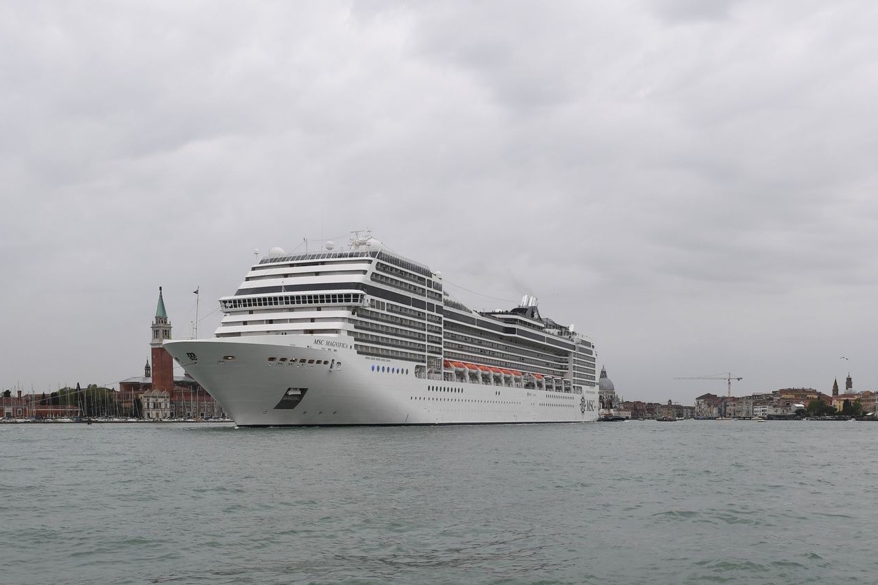 Ein Kreuzfahrtschiff fährt an der Lagunenstadt Venedig von einem Schlepper gezogen vorbei.
