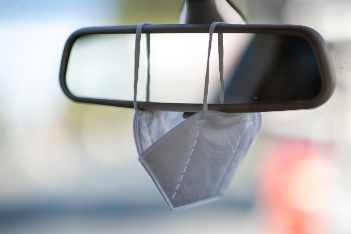 Eine FFP2-Maske hängt am Rückspiegel eines Autos (Symbolbild).