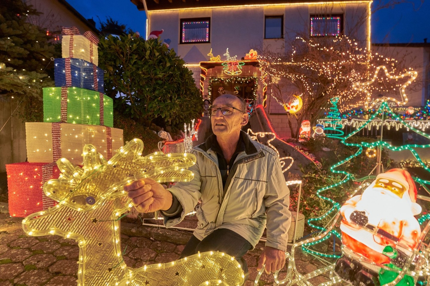 Rentner Josef Johann baut vor seinem Haus im Moseldorf Klotten bunte leuchtende Weihnachtsdekoration auf.
