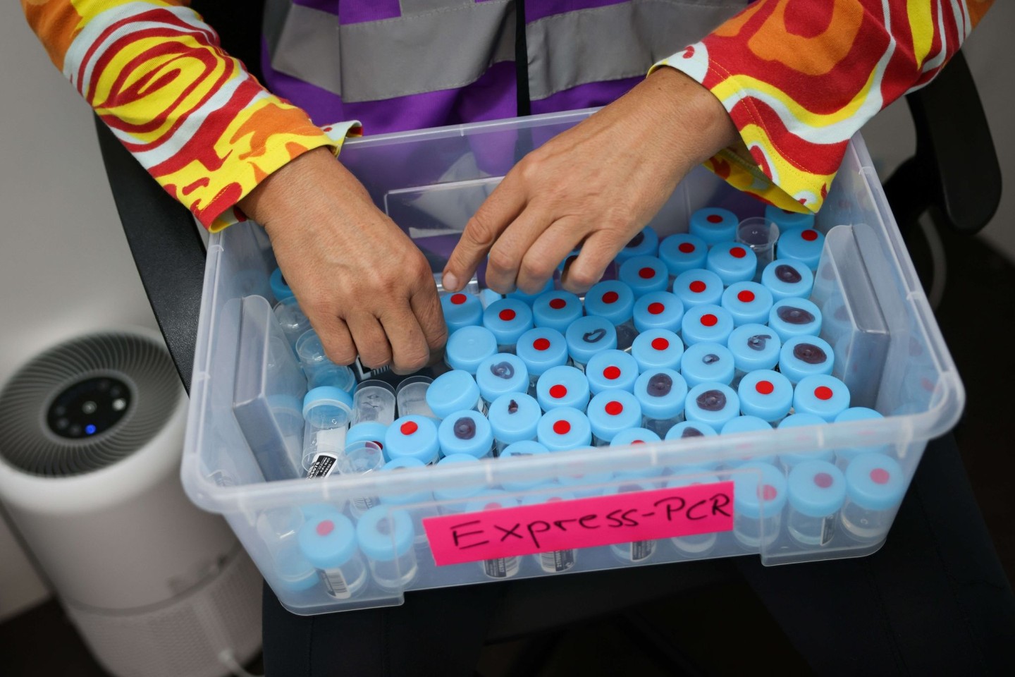 Eine Mitarbeiterin sortiert noch unbenutzte Behälter für einen PCR-Gurgeltest in einem Testcenter für Corona-Schnelltests (Antigentest) und Corona-PCR-Tests.