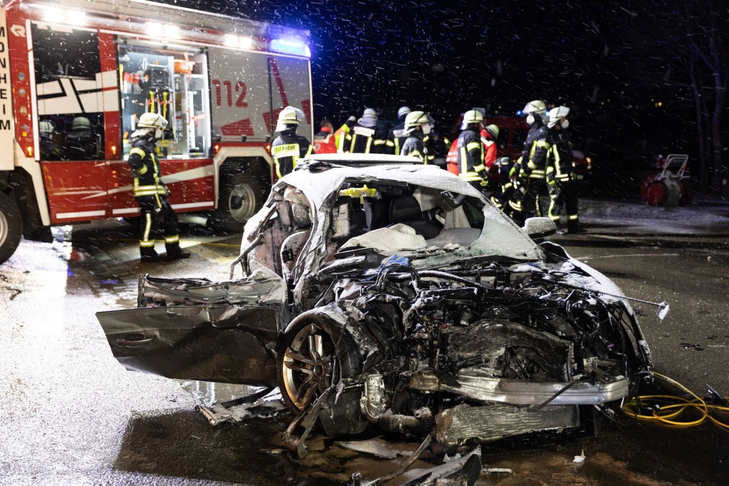 Feuerwehrleute stehen im April 2022 bei Monheim nach der Kollision hinter dem Autowrack einer 54 Jahre alten Frau. Sie starb noch am Unfallort.