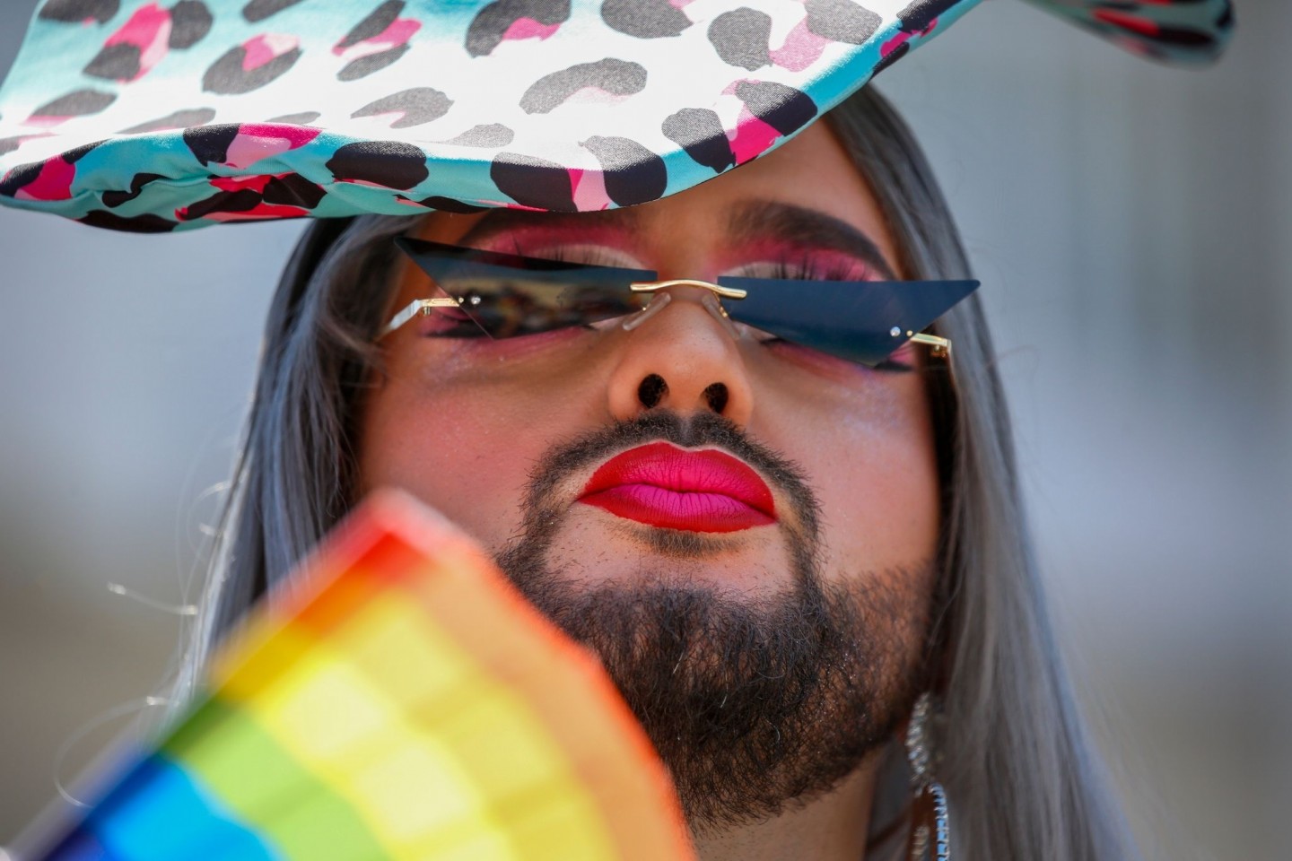 Ein Teilnehmer fächert sich bei der jährlichen Pride Parade Luft mit einem regenbogenfarbenen Fächer zu.