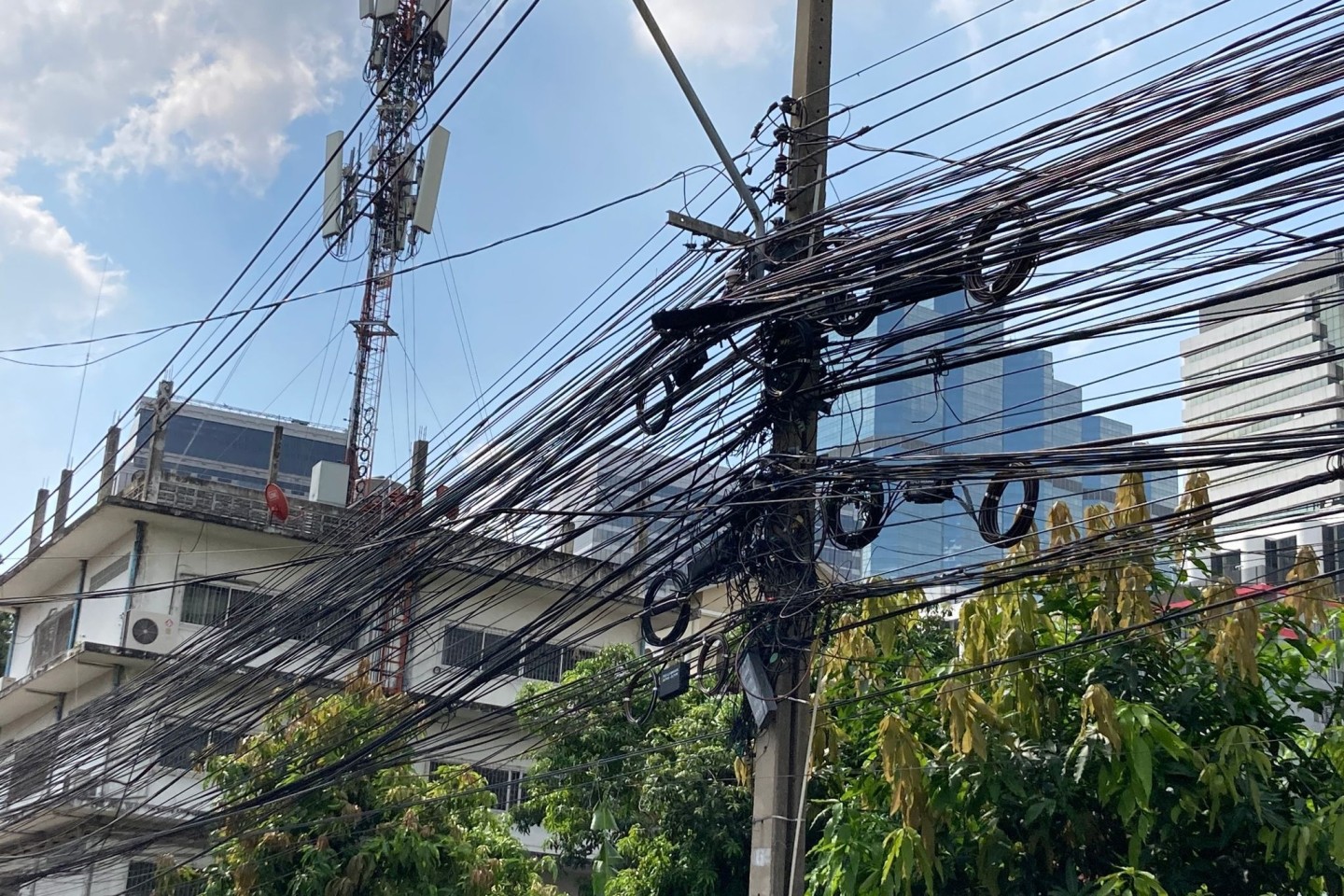 Strom- und Telefonleitungen werden in Thailand nicht unterirdisch verlegt, sondern spannen sich in massiven schwarzen Bündeln von Mast zu Mast.
