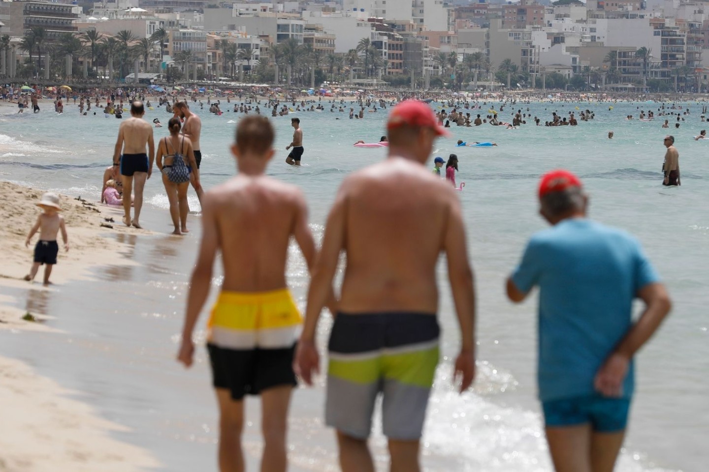 Menschen laufen am Strand von Arenal auf Mallorca.
