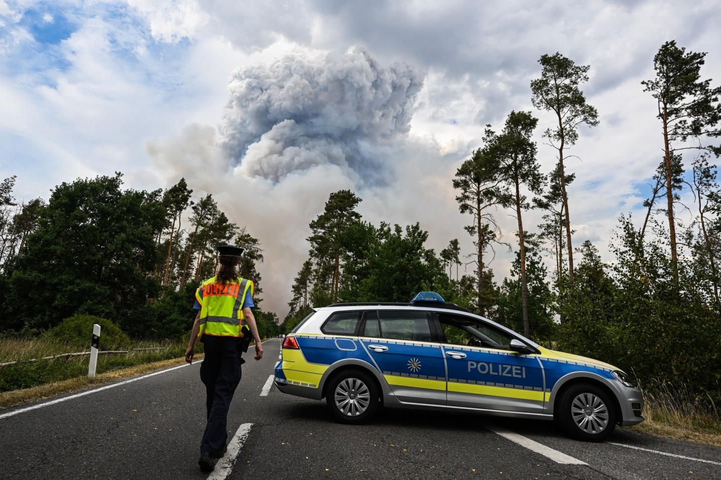 Ein Polizeiauto sperrt die Straße im Waldbrandgebiet in der sächsischen Gohrischheide ab.