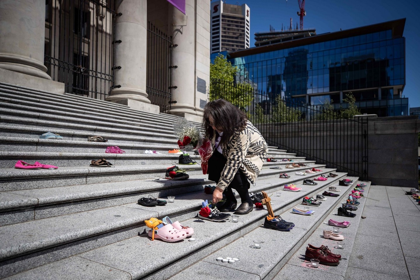 Eine Angehörige einer indigenen Volksgruppe legt eine Rose auf eines von 215 Paar Kinderschuhen auf den Stufen der Vancouver Art Gallery.