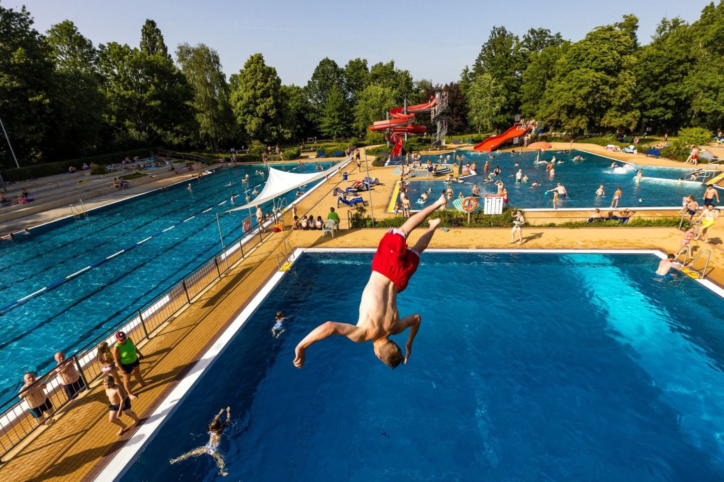 Es ist heiß. Ein junger Mann in Brandenburg springt ins Wasserbecken.