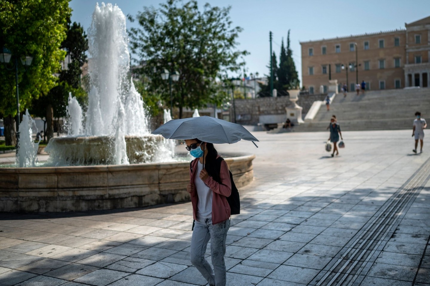 Eine Frau schützt sich bei Temperaturen über 40 Grad in Athen mit einem Schirm vor Sonne und Hitze.